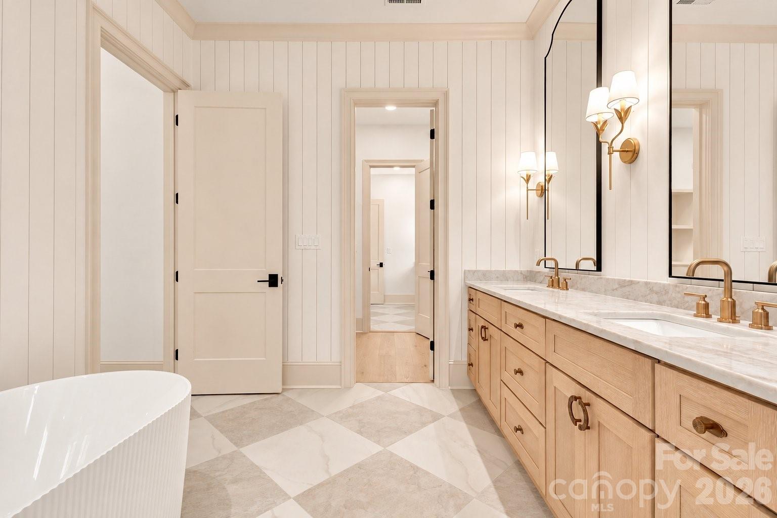 Bathroom with a freestanding tub, double vanity, brass fixtures, and checkerboard tile floor.