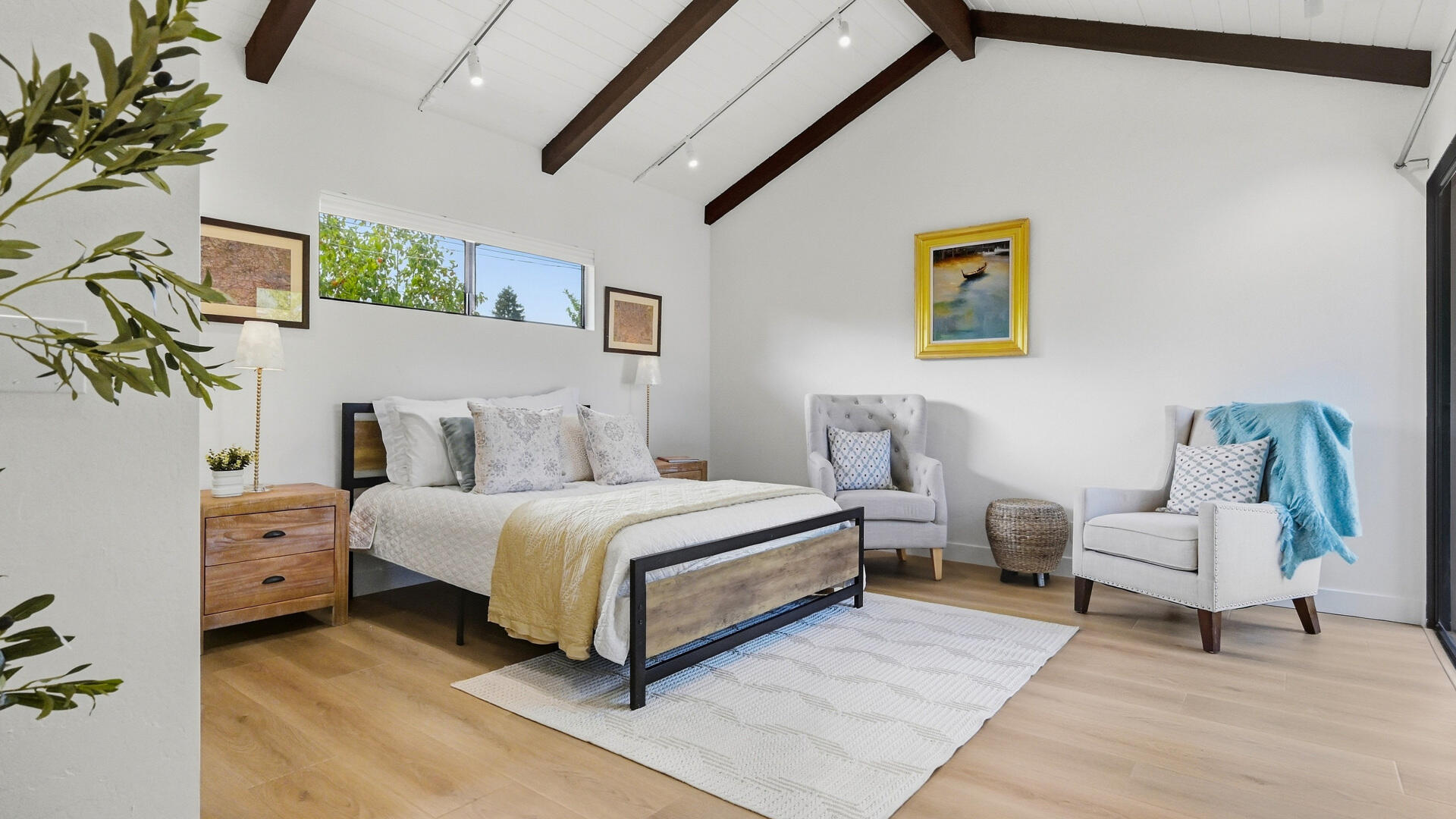 Furnished bedroom with exposed ceiling beams, clerestory windows, and a sitting area.