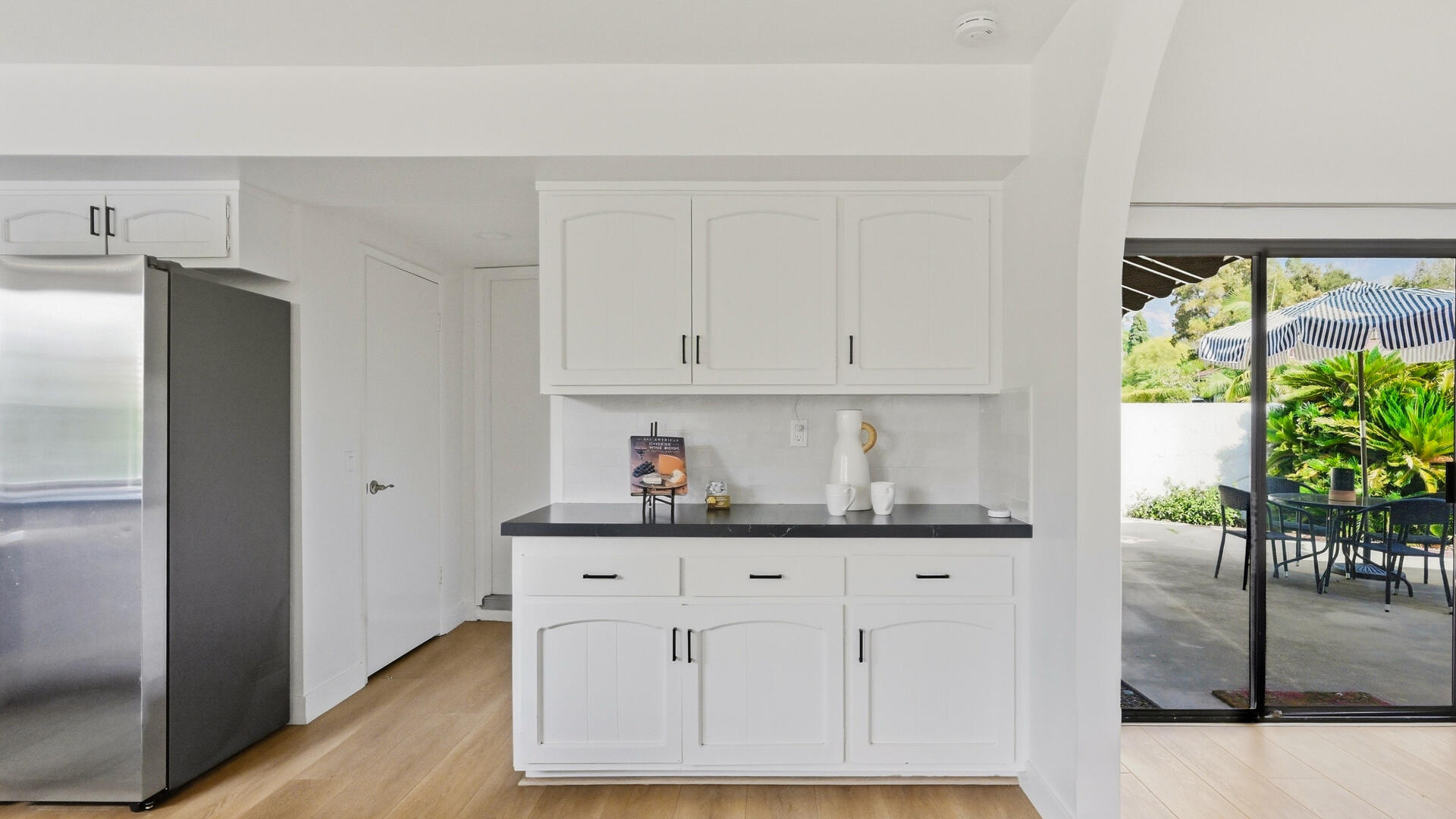 White kitchen with dark countertops and sliding glass doors opening to a furnished patio.