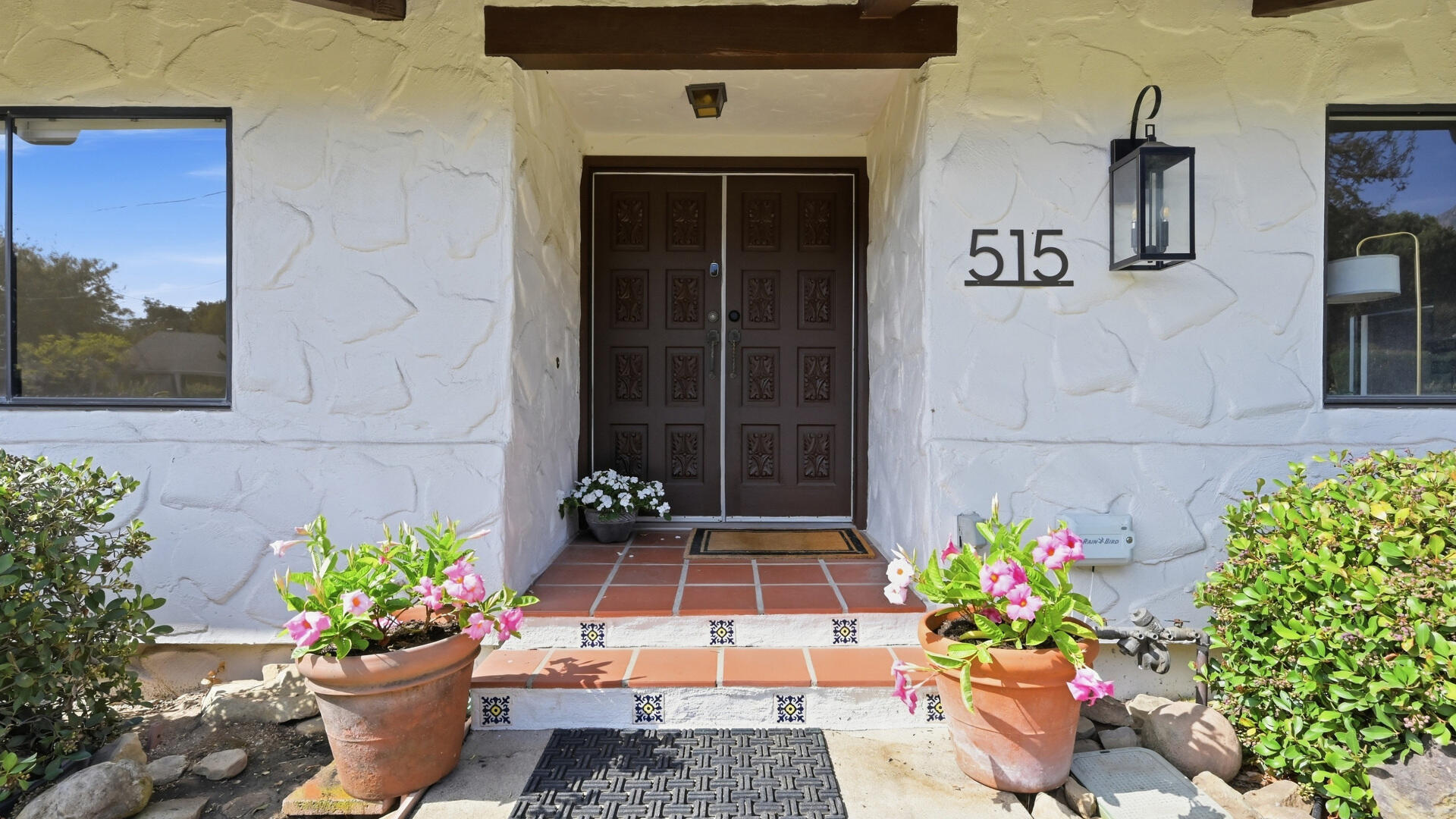 Front entrance with carved double doors, tiled steps, and potted flowers at 515 Calle Alamo.