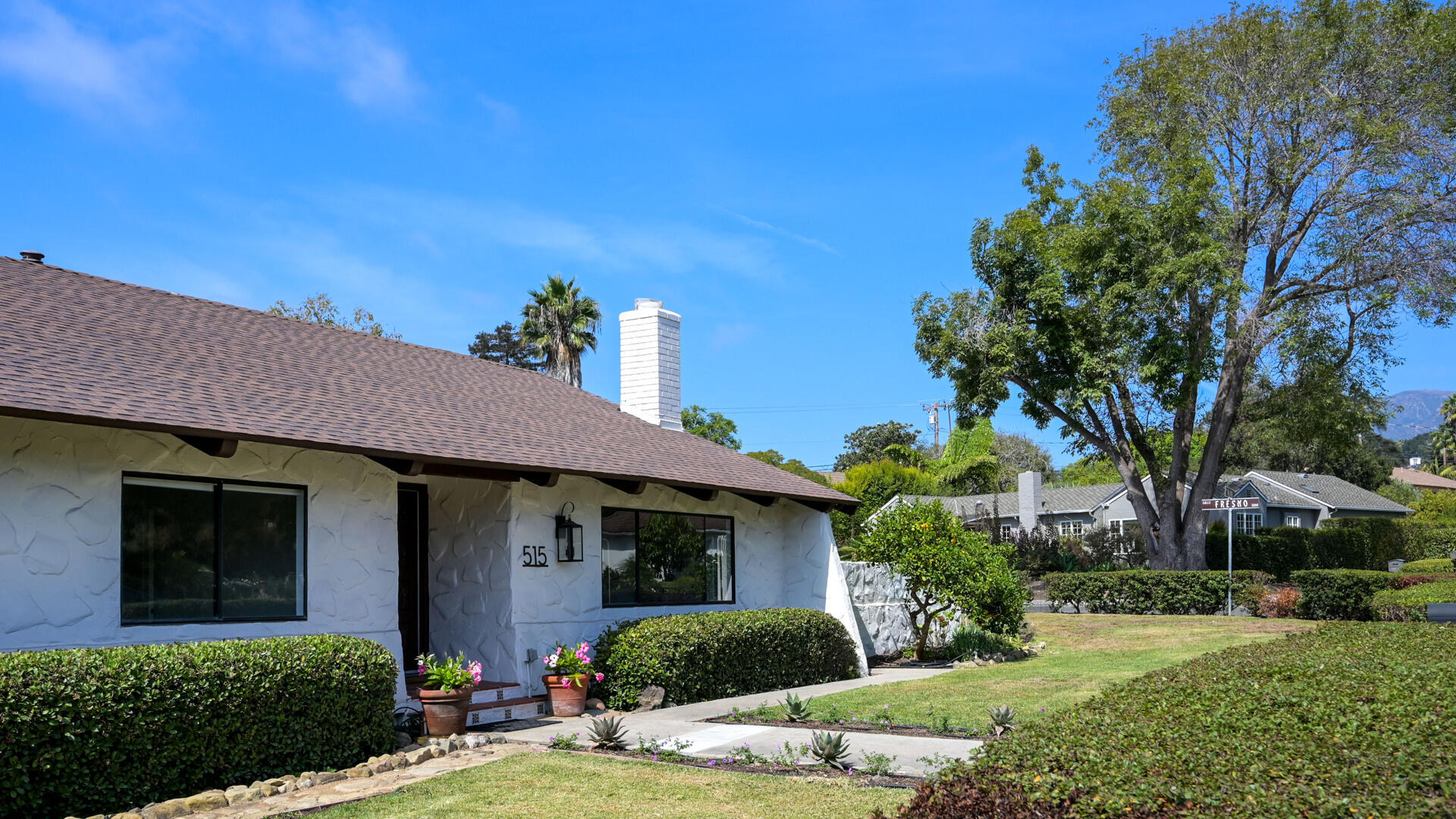 White stucco single-story home with a brown roof, landscaped lawn, and address 515 beside the entry.
