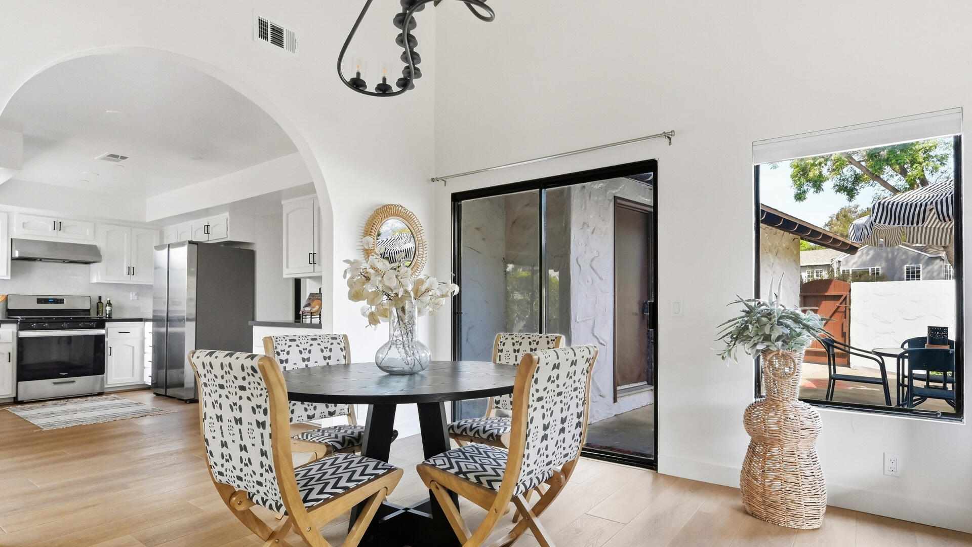 Dining area with a round table and patterned chairs beside an open kitchen and patio doors.
