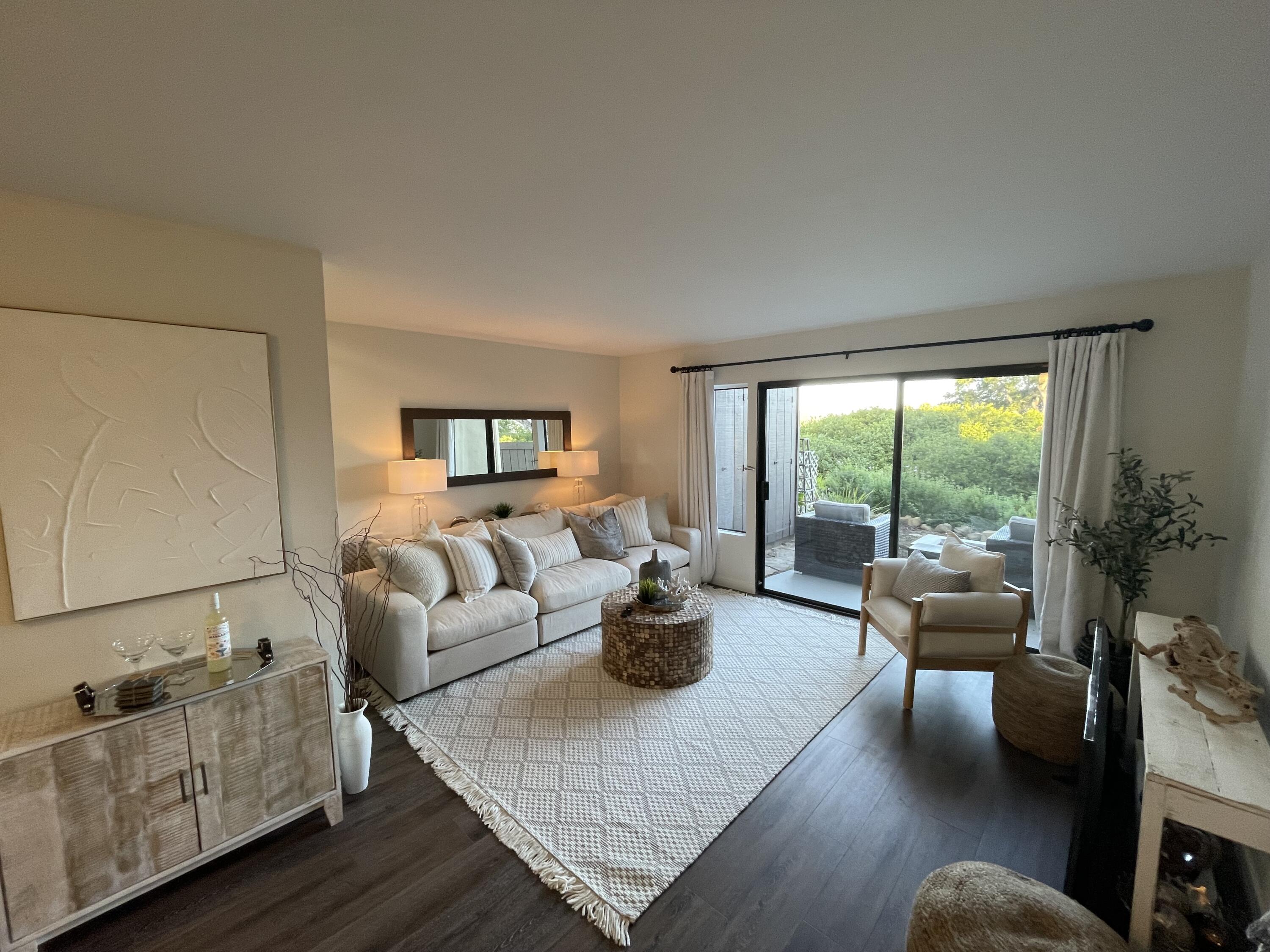 Living room with a cream sofa, patterned rug, and sliding glass doors opening to a garden patio.