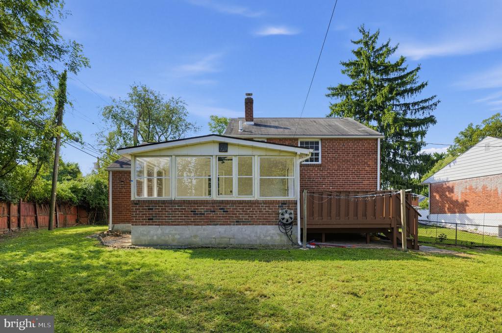 Brick home with a large screened porch, raised deck, and spacious green backyard.