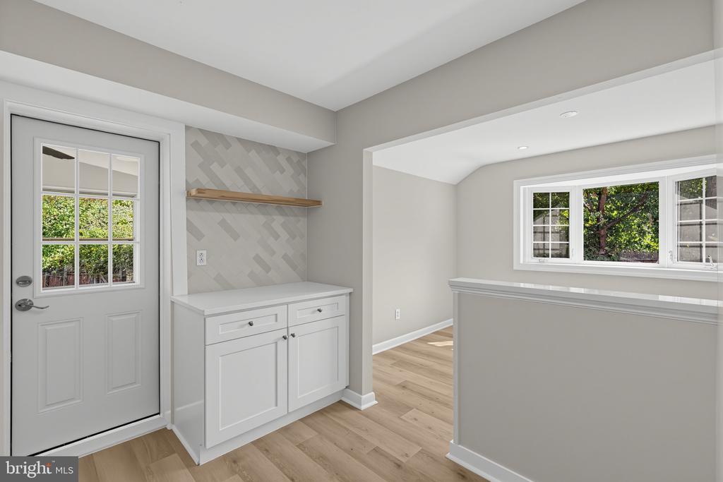 Mudroom with built-in white cabinets, a wood shelf, and a glass-paneled exterior door.