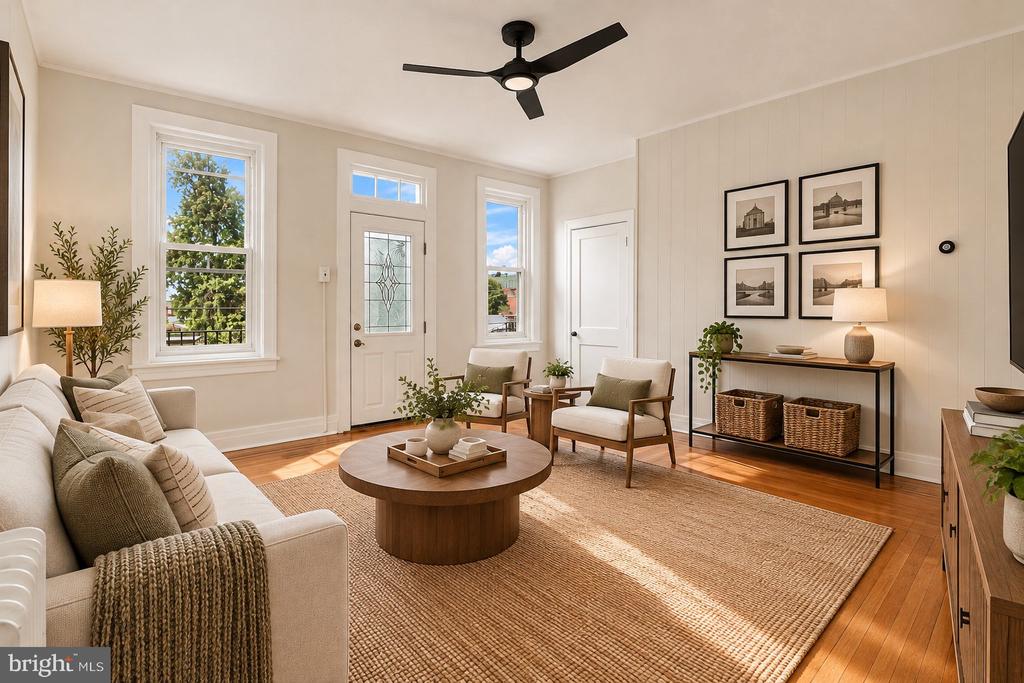 Living room with a white sofa, wood coffee table, and tall windows beside the entry door.