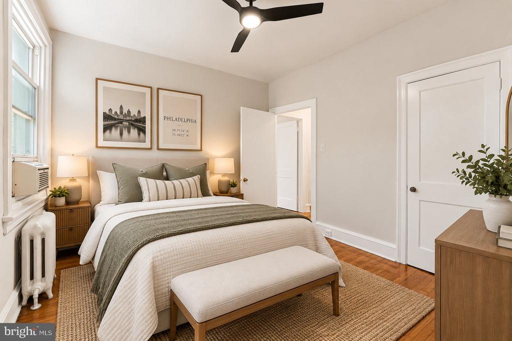 Staged bedroom with a tufted bed, Philadelphia wall art, and a large window.