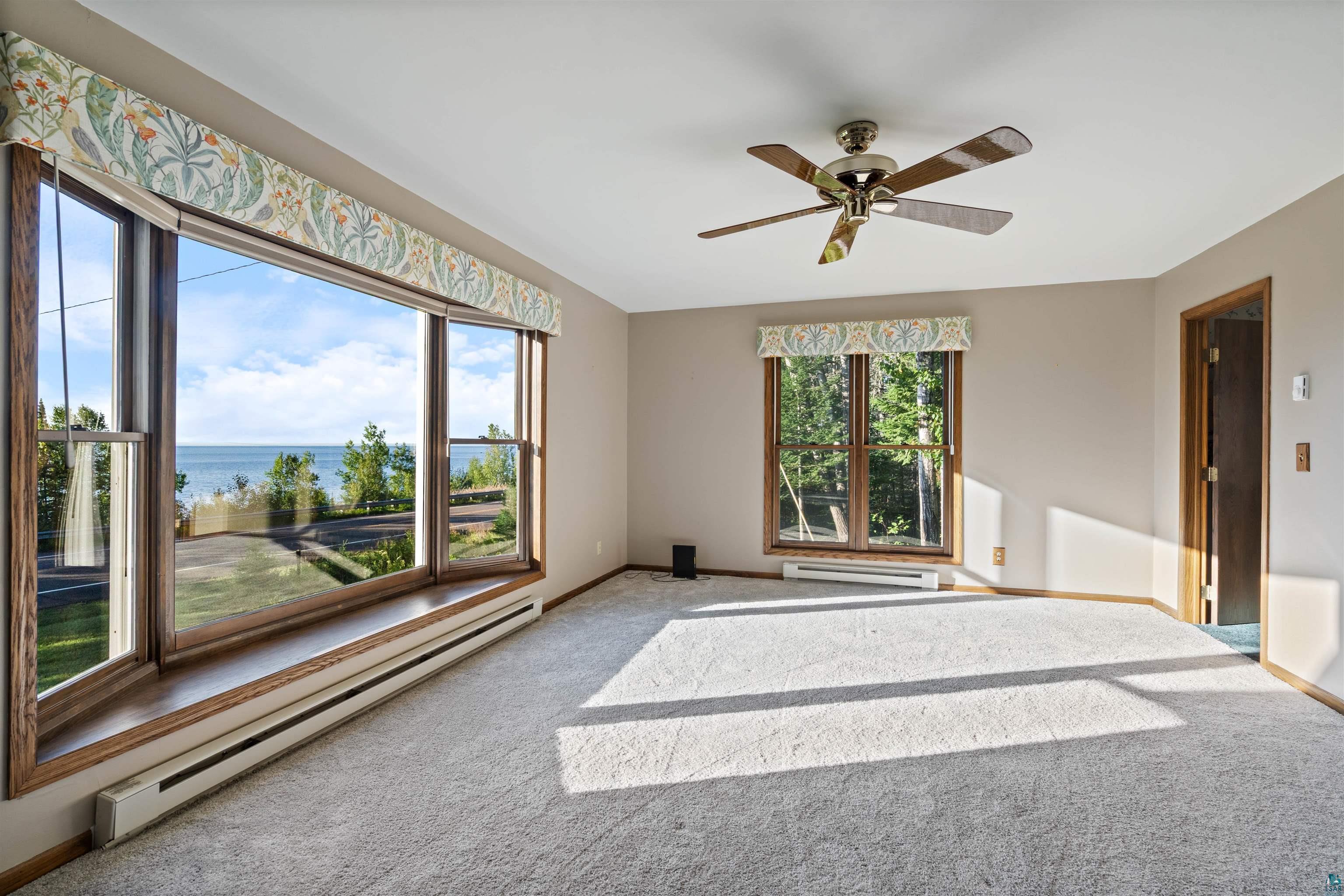 Unfurnished room with large windows overlooking the lake and shoreline.
