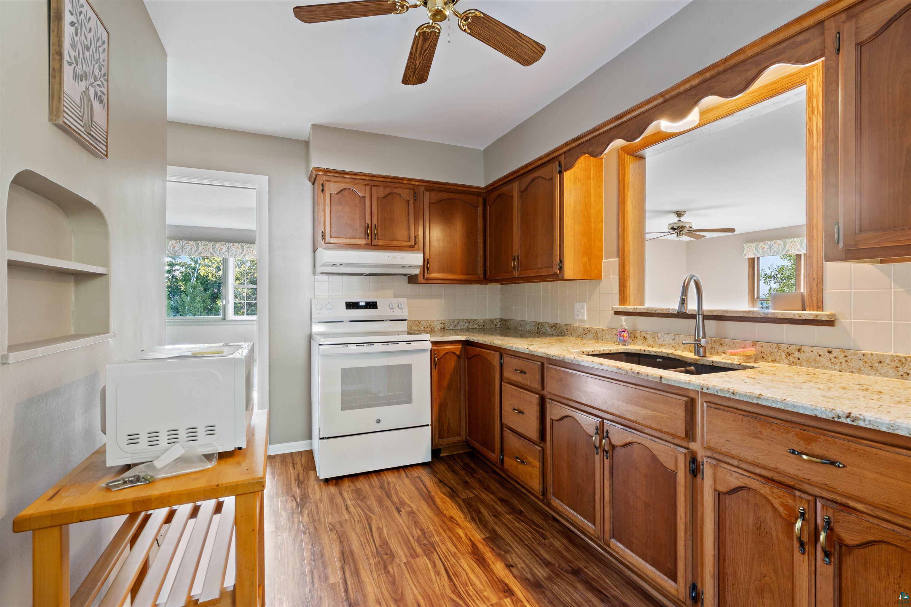 Kitchen with warm wood cabinets, granite counters, and a pass-through to an adjoining room.