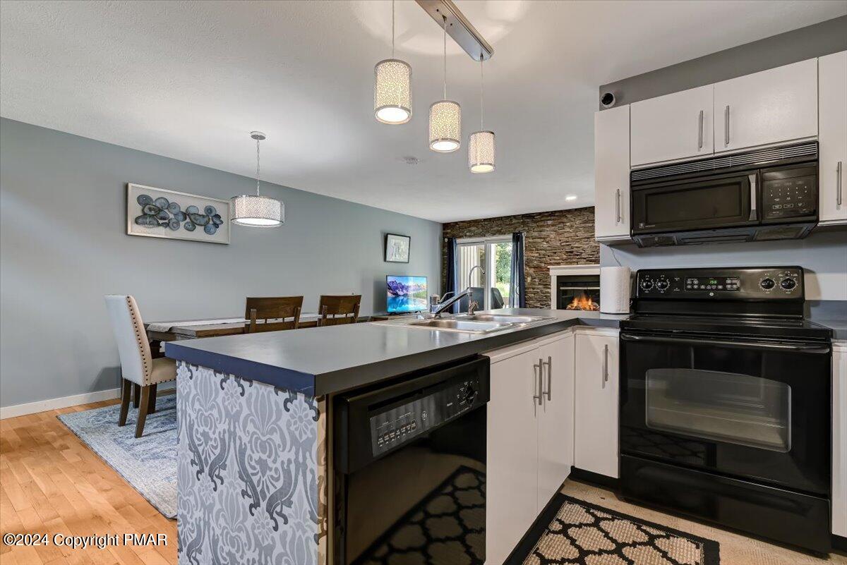 Kitchen with a large patterned island, dining area, and stone fireplace.