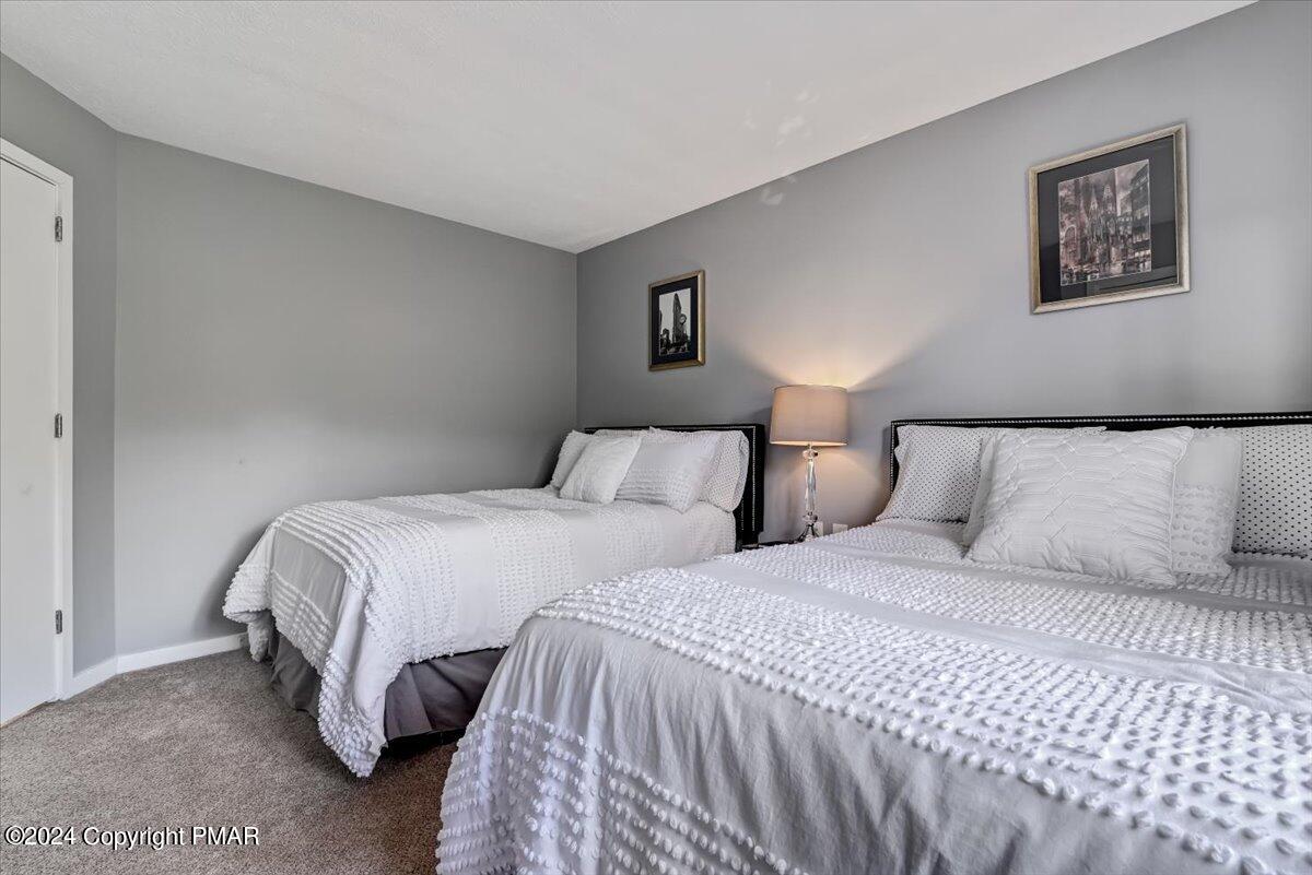 Bedroom with two white-covered beds, gray walls, and a bedside lamp.