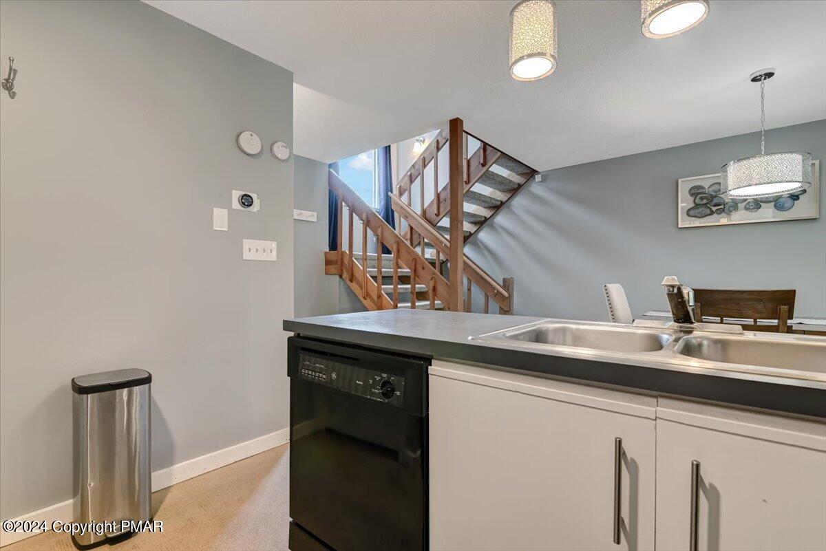 Kitchen with a double-basin sink and dishwasher, with a wooden staircase behind it.