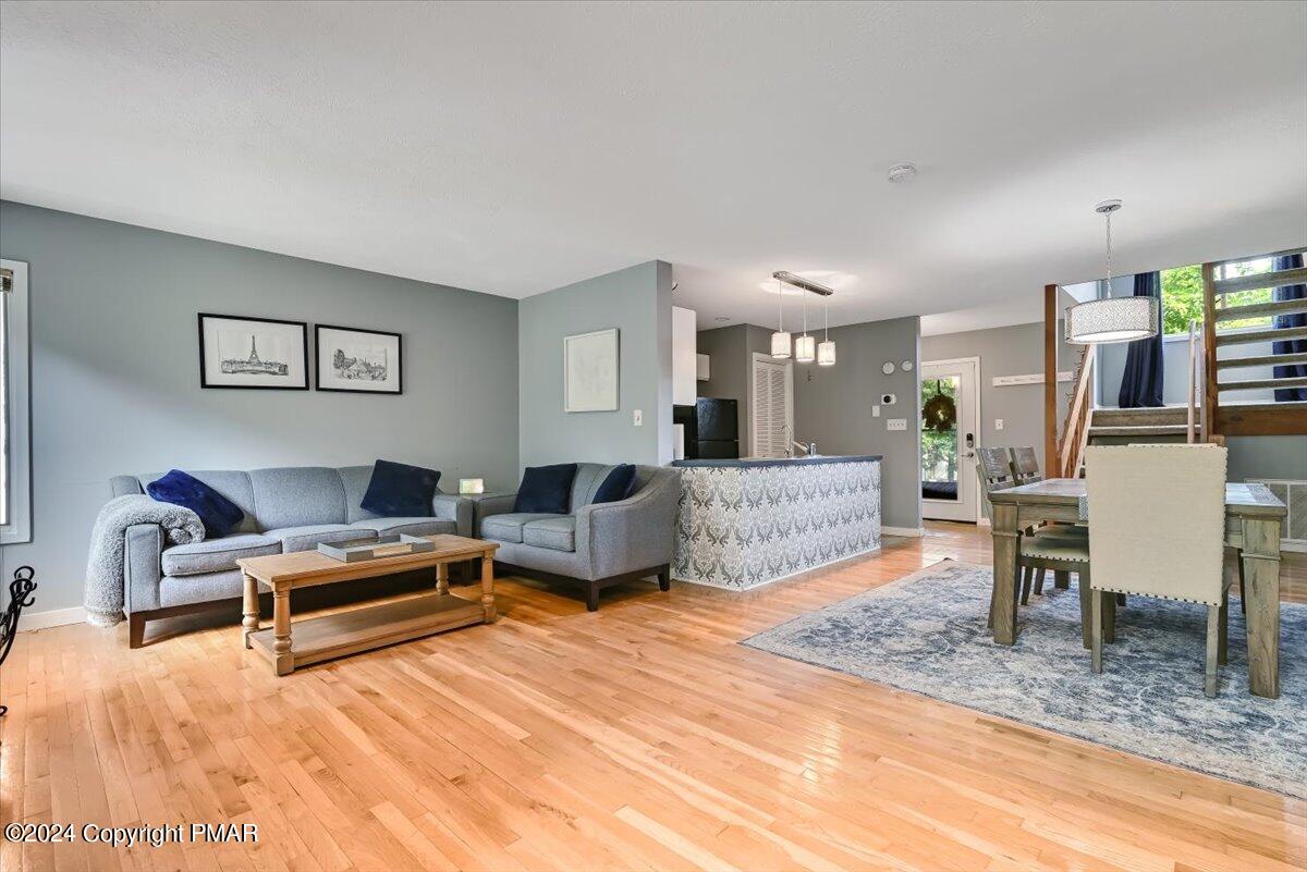 Open-plan living and dining area with a gray sectional, patterned kitchen island, and hardwood floors.