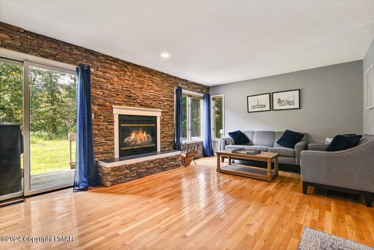 Living room with a stone fireplace, gray sectional sofa, hardwood floors, and sliding doors to the yard.