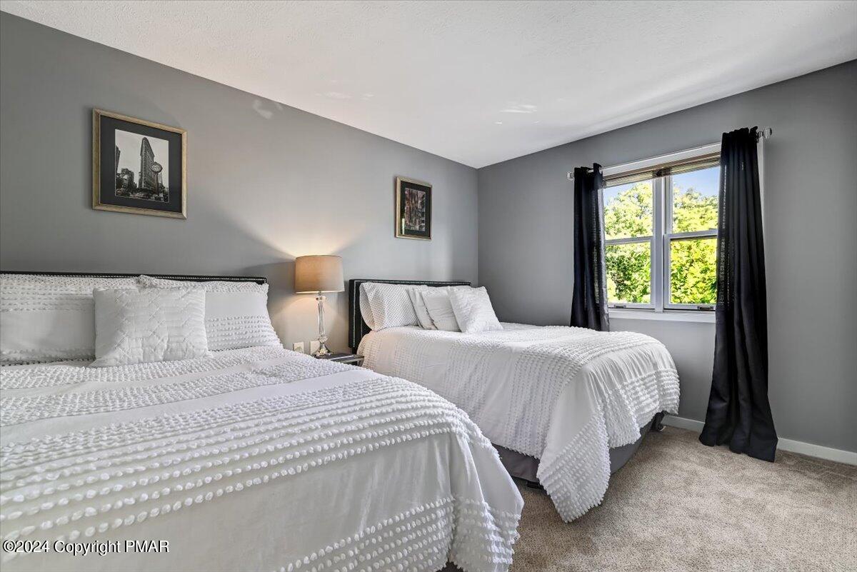 Bedroom with two white beds, gray walls, and a window framed by black curtains.