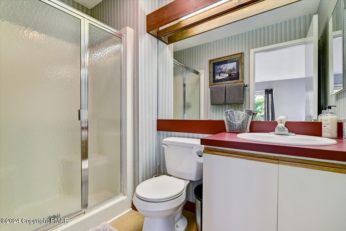 Bathroom with frosted-glass shower, striped wallpaper, and a burgundy-red vanity countertop.