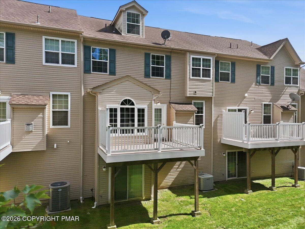 Townhouse rear with elevated white-railed decks, tan siding, and a walkout lower level.