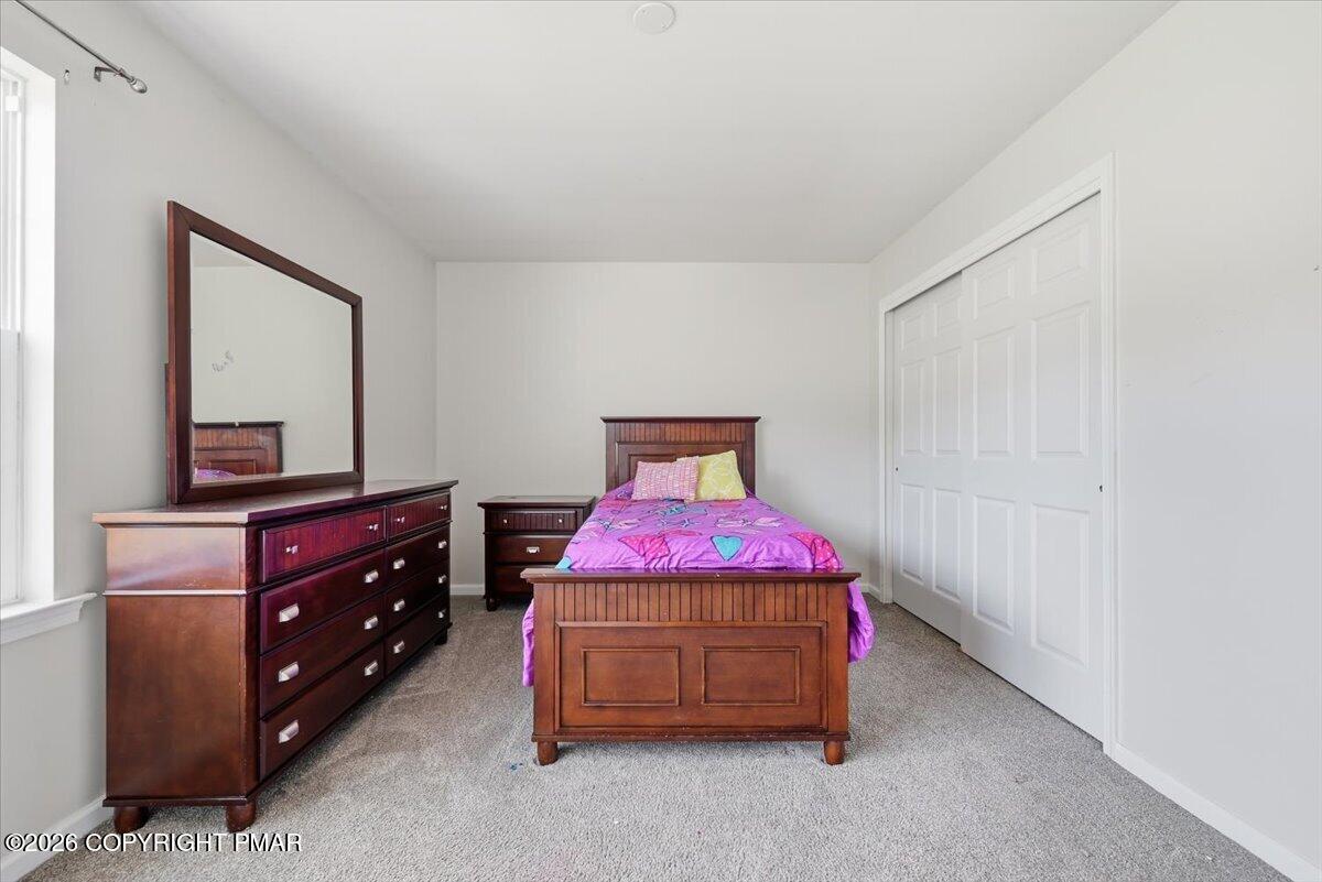 Bedroom with a wooden bed, purple bedding, matching dresser, and white sliding-door closet.