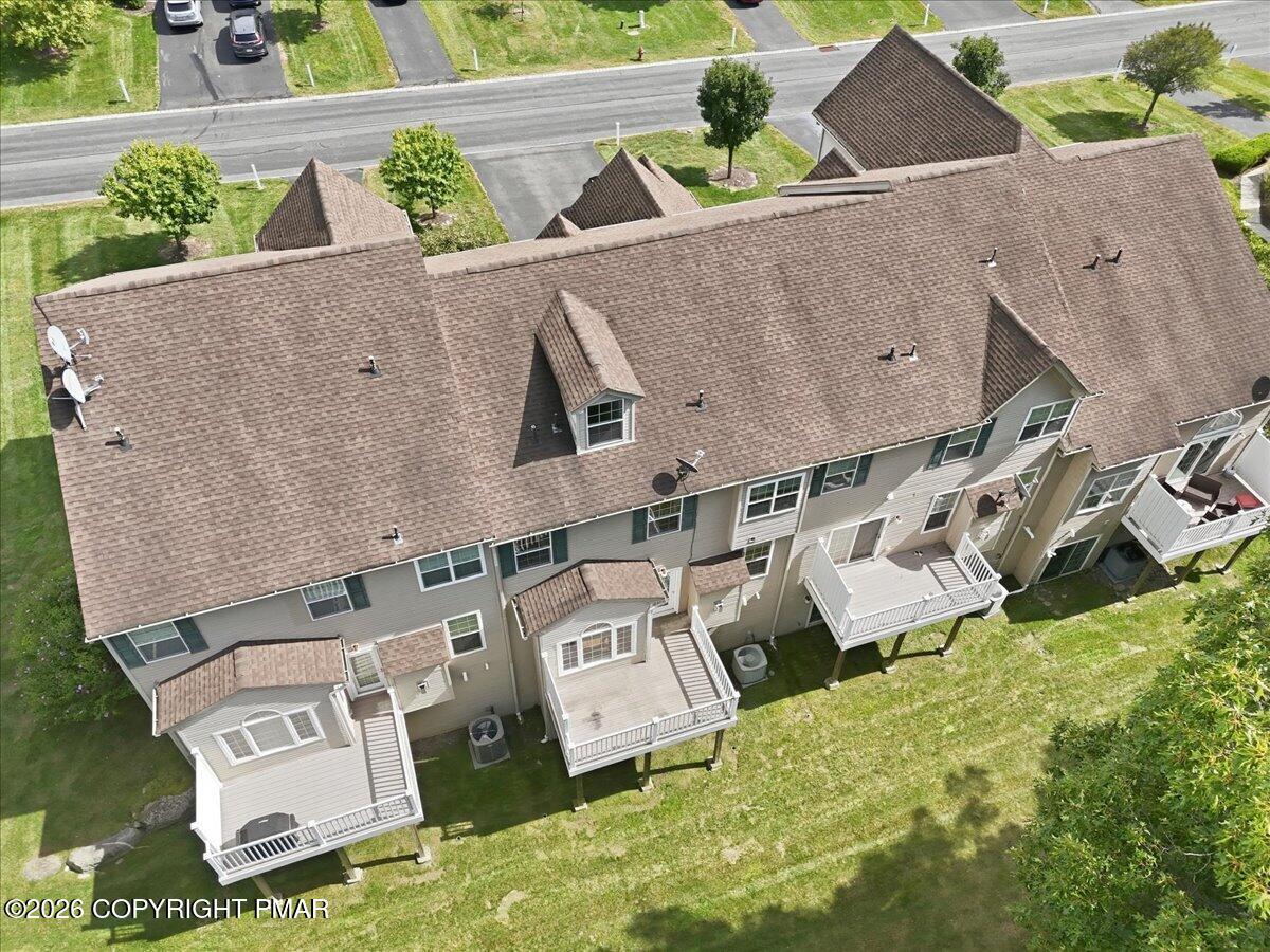 Aerial view of an attached residential building with a long roof and several rear decks.