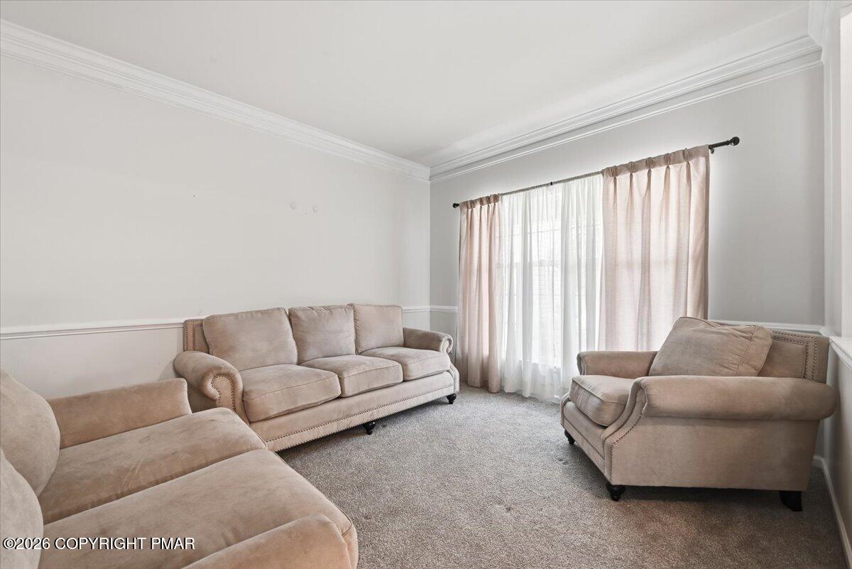 Living room with beige seating, carpet, and a large curtained window.
