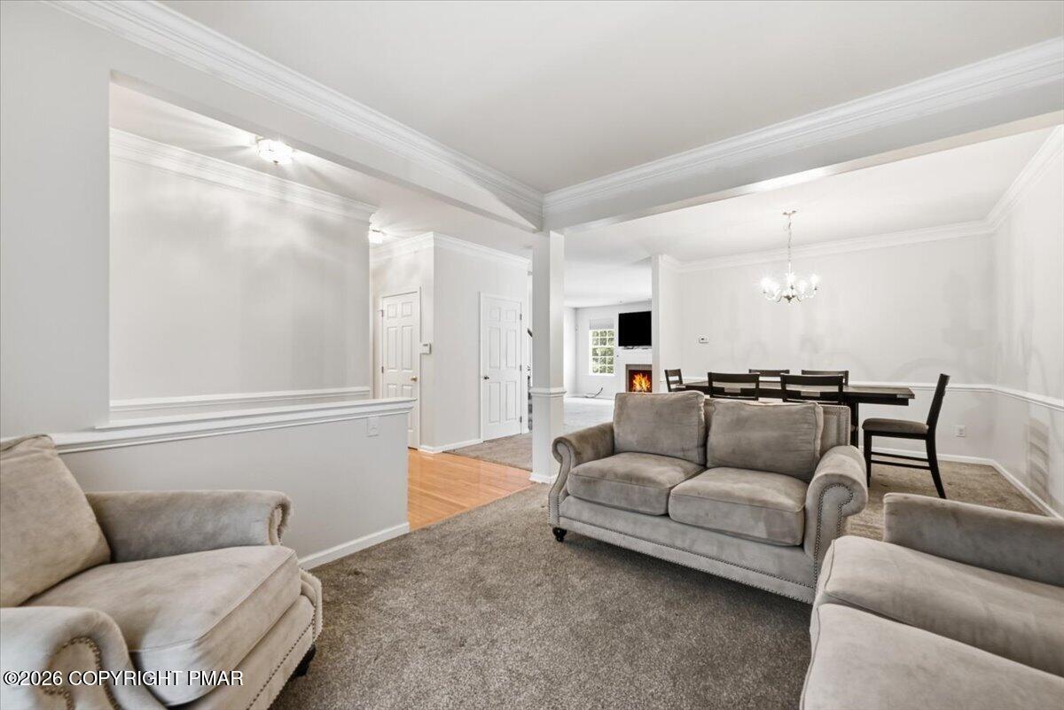 Furnished living room with gray sofas, crown molding, and an adjoining dining area.
