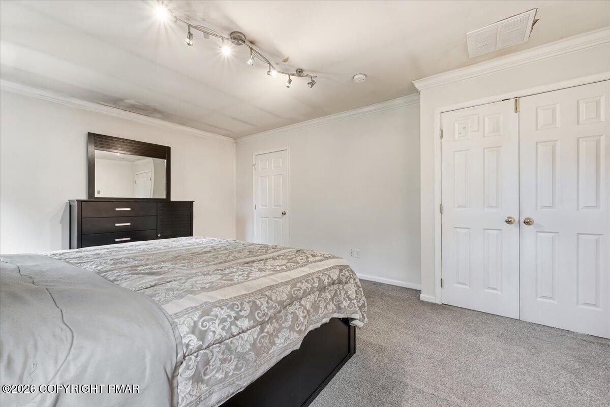 Bedroom with a patterned bed, dark dresser and mirror, and white double closet doors.
