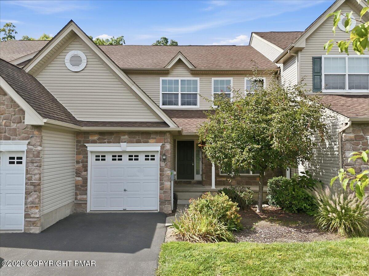 Two-story home with stone accents, white garage door, and landscaped front yard.
