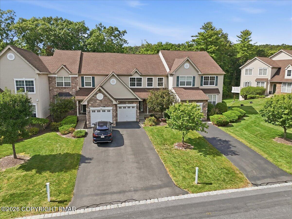 Attached home with stone accents, multiple garages, and a landscaped driveway