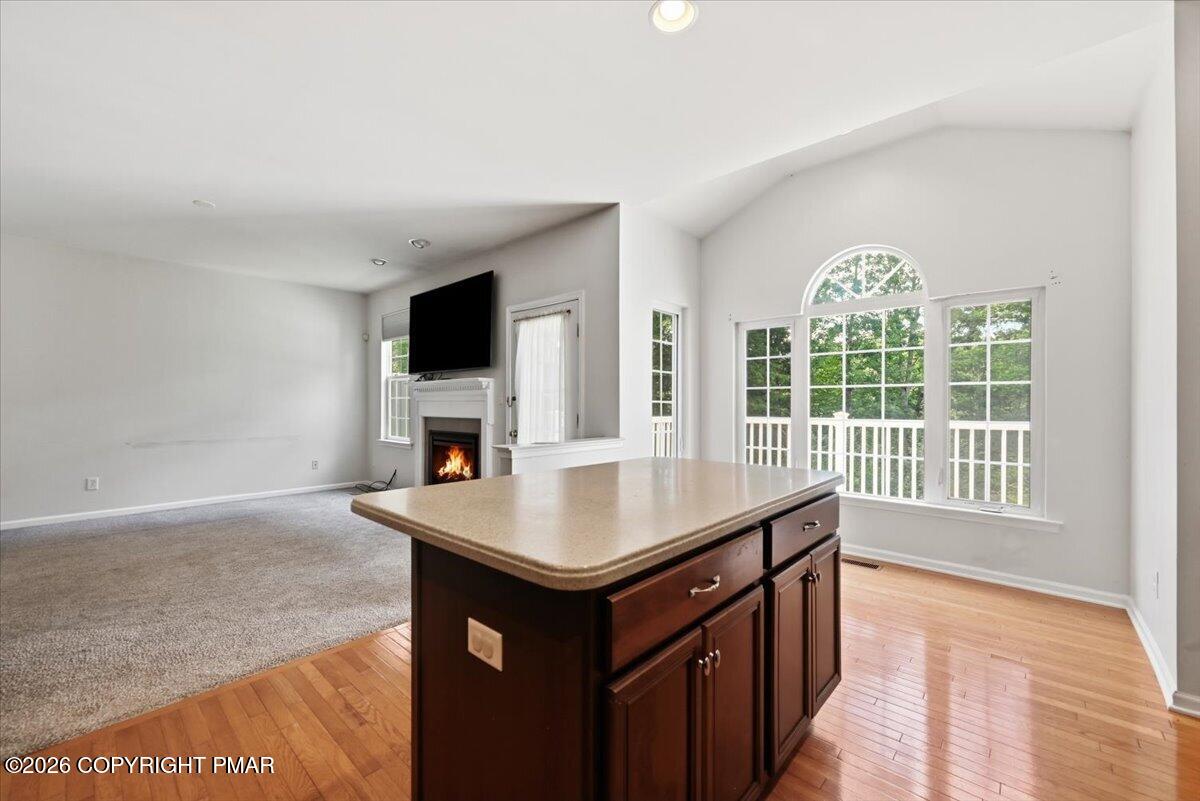 Open kitchen and living area with a wood island, fireplace, and large arched window.