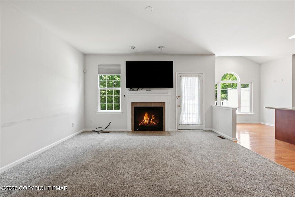 Living room with gray carpet, a fireplace, and a large television above the mantel.