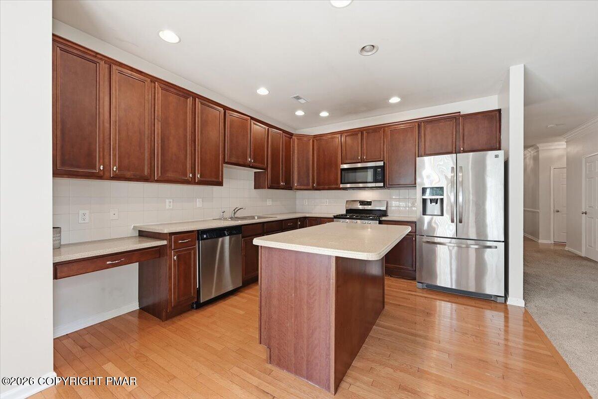 Kitchen with dark wood cabinets, a central island, stainless steel appliances, and hardwood floors.