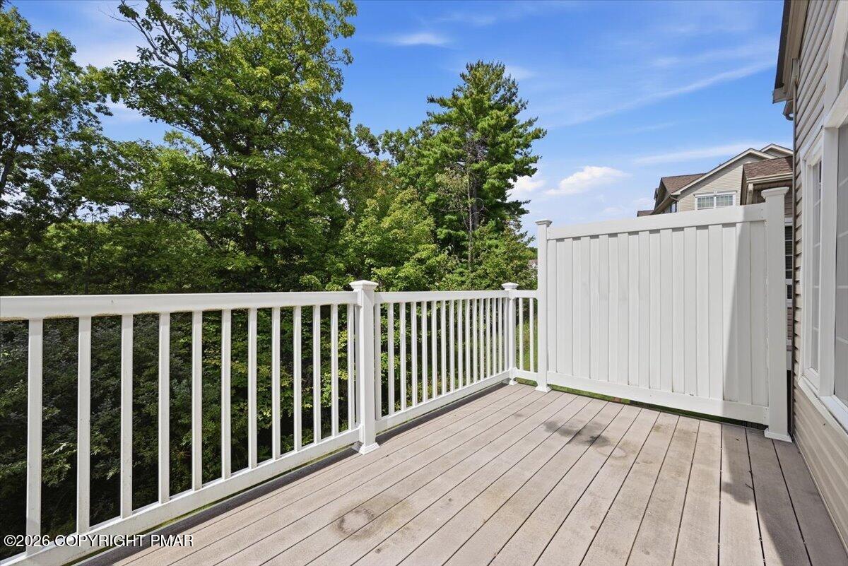 Elevated deck with white railings and privacy panel overlooking leafy trees.