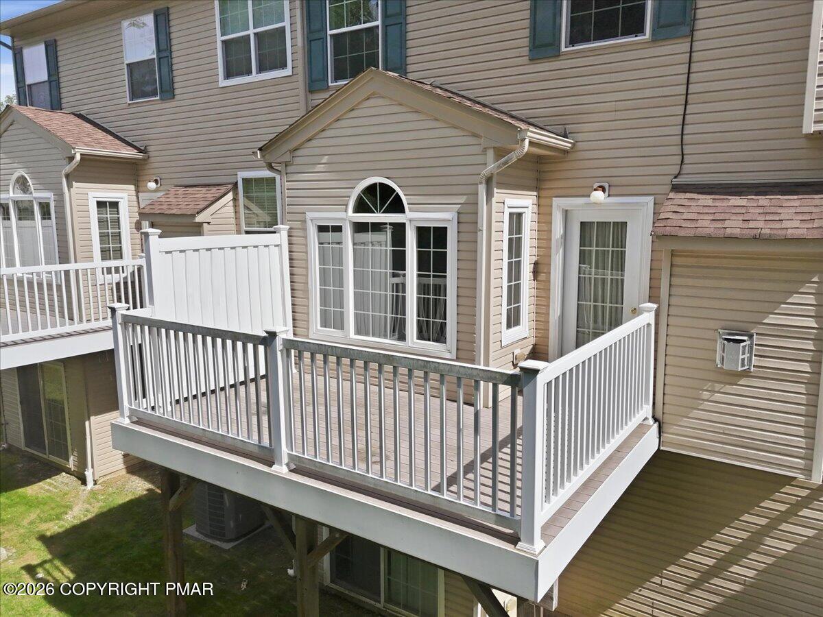 Raised deck with gray flooring and white railings beside a sliding glass door.