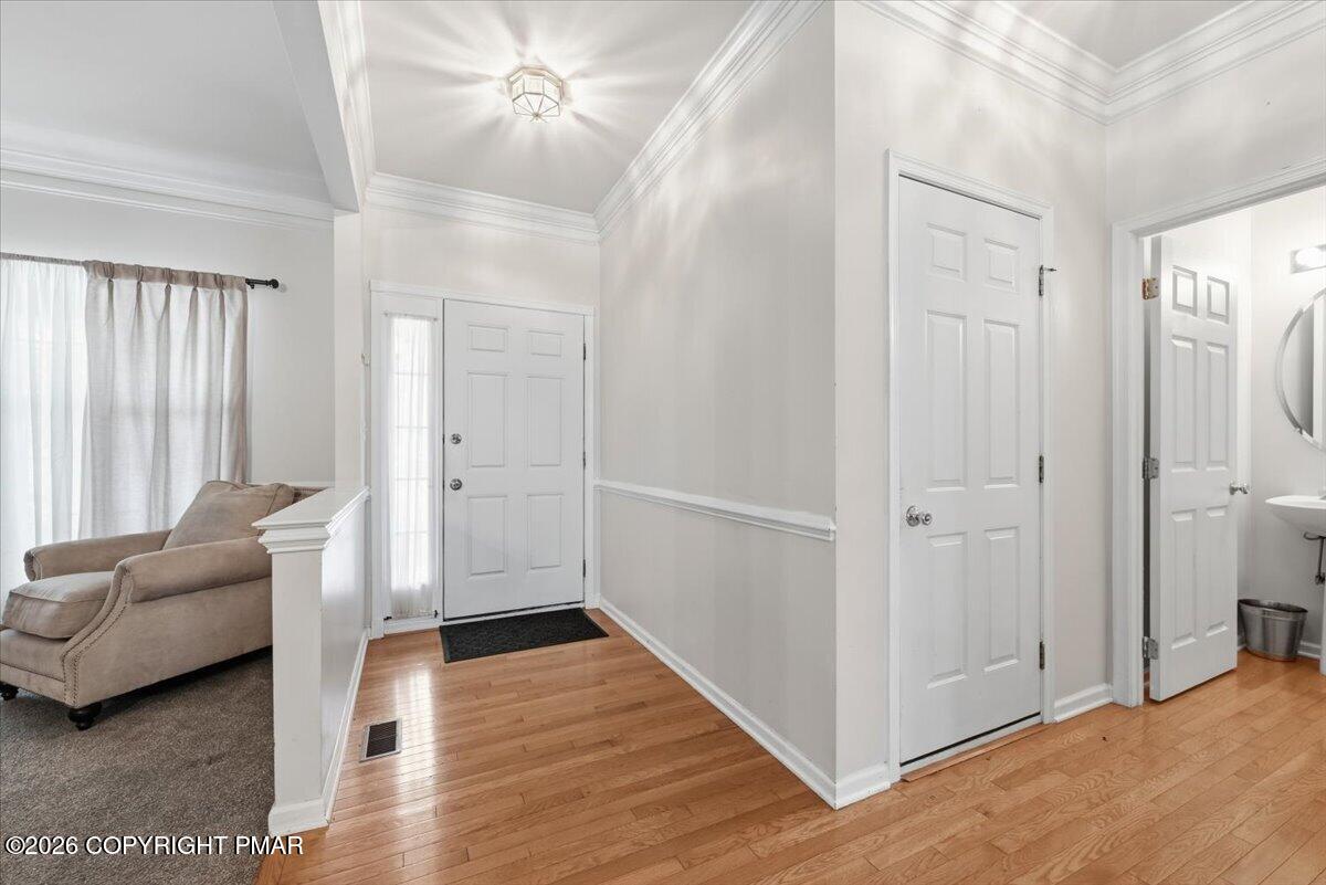 Entry foyer with hardwood floors, white front door, and adjoining living room.