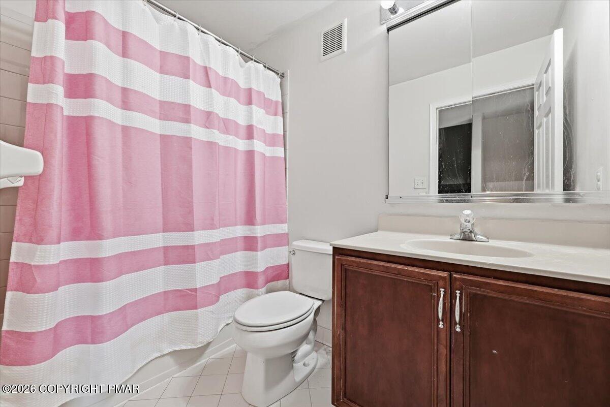 Bathroom with a pink-and-white striped shower curtain and dark wood vanity.