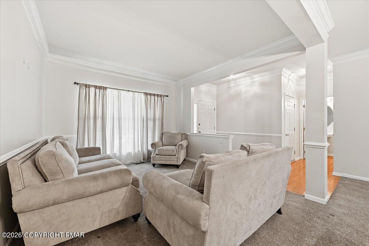 Living room with beige sofas, a curtained window, and an adjoining hardwood-floored hall.