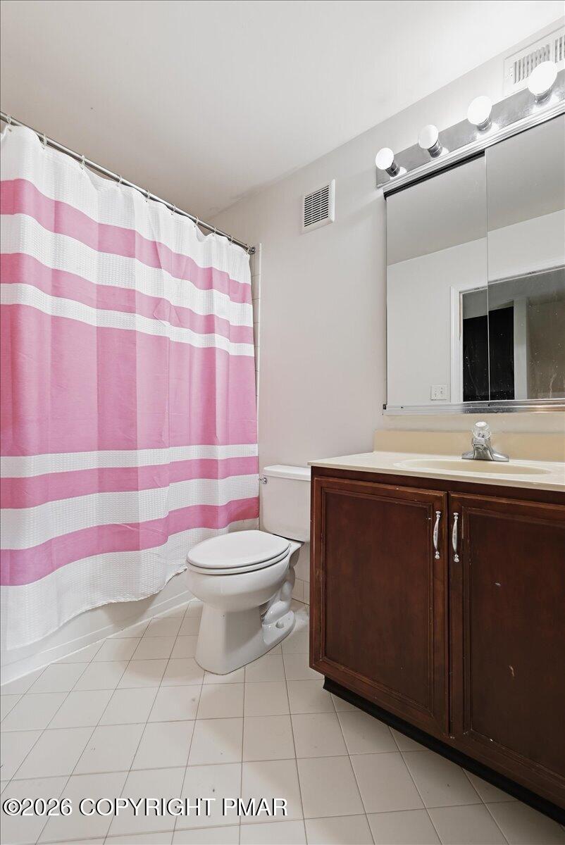Bathroom with a pink-and-white striped shower curtain and dark wood vanity.