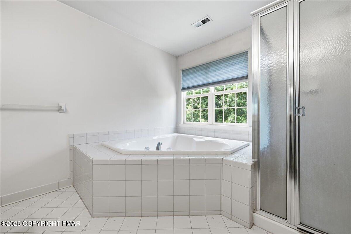 Bathroom with a large corner soaking tub, tiled surround, and glass-enclosed shower.