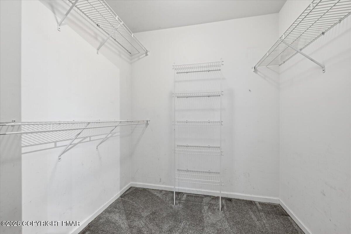 Walk-in closet with gray carpet and extensive white wire shelving.