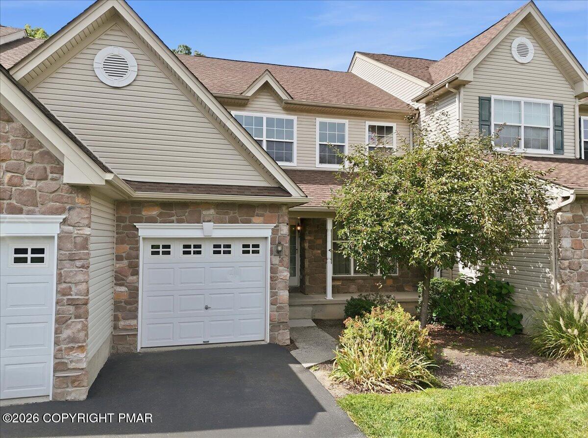 Two-story home with stone accents, multiple gables, and a white garage door.