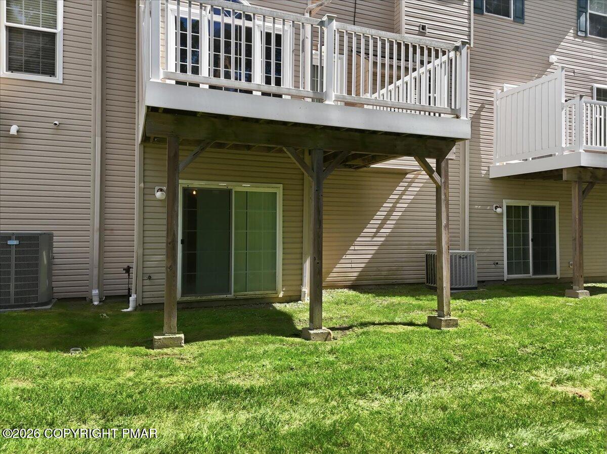 Rear exterior with elevated white-railed decks above sliding glass doors and a green lawn.