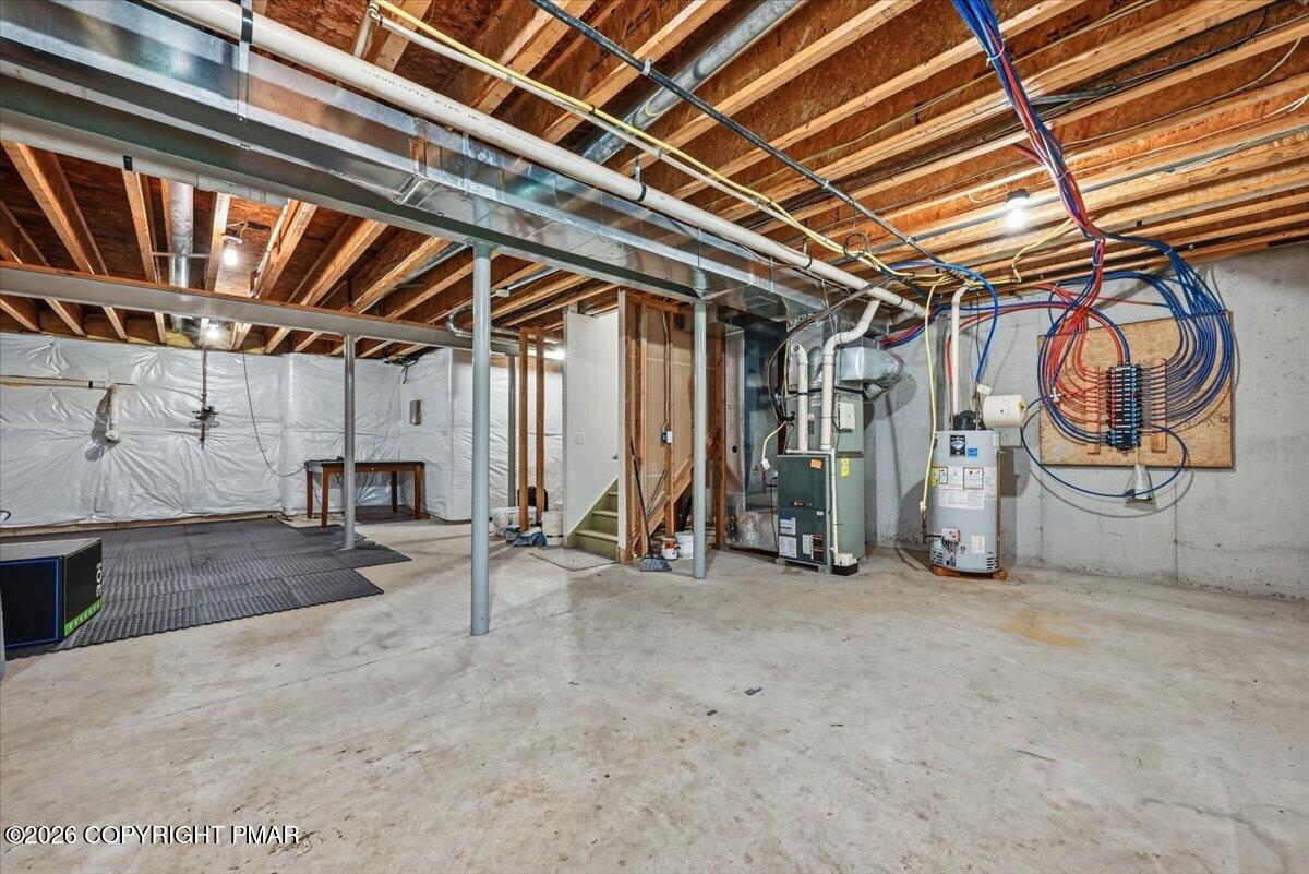 Unfinished basement with exposed ceiling joists, concrete floor, and visible mechanical equipment.