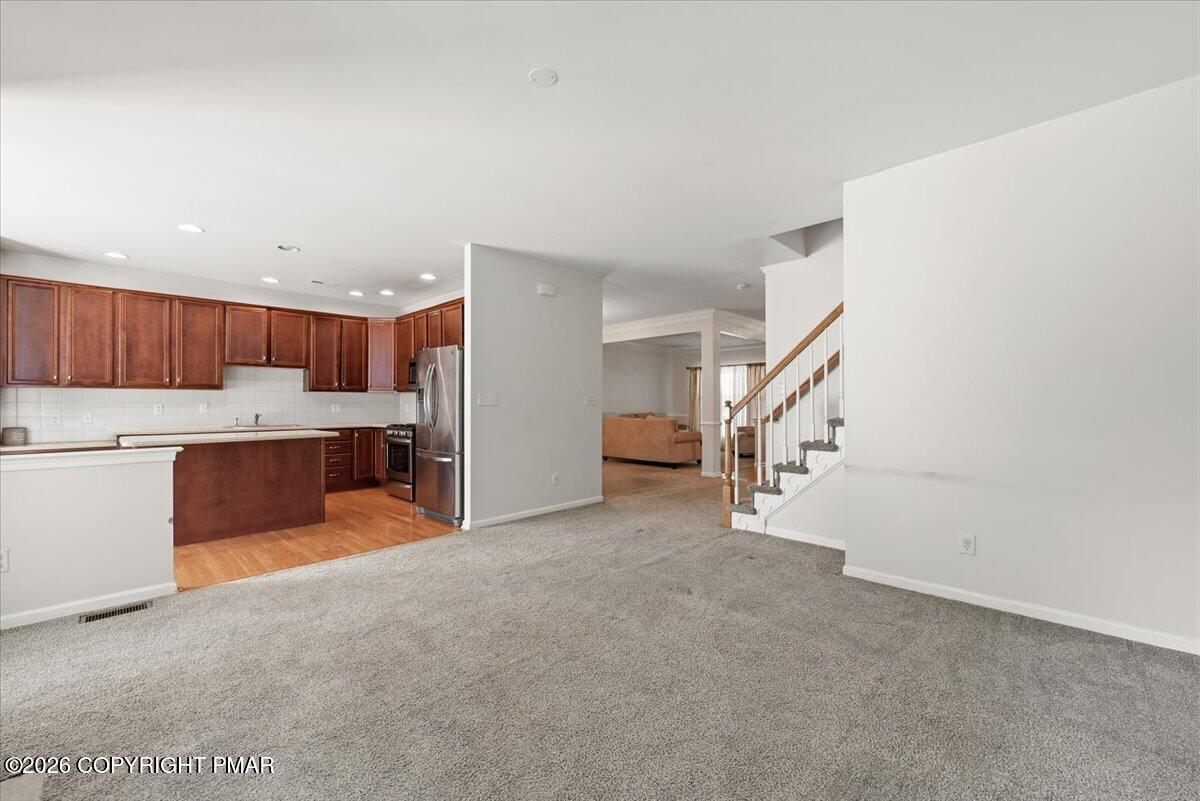 Open-plan living area with a dark wood kitchen, stainless-steel appliances, and a staircase.