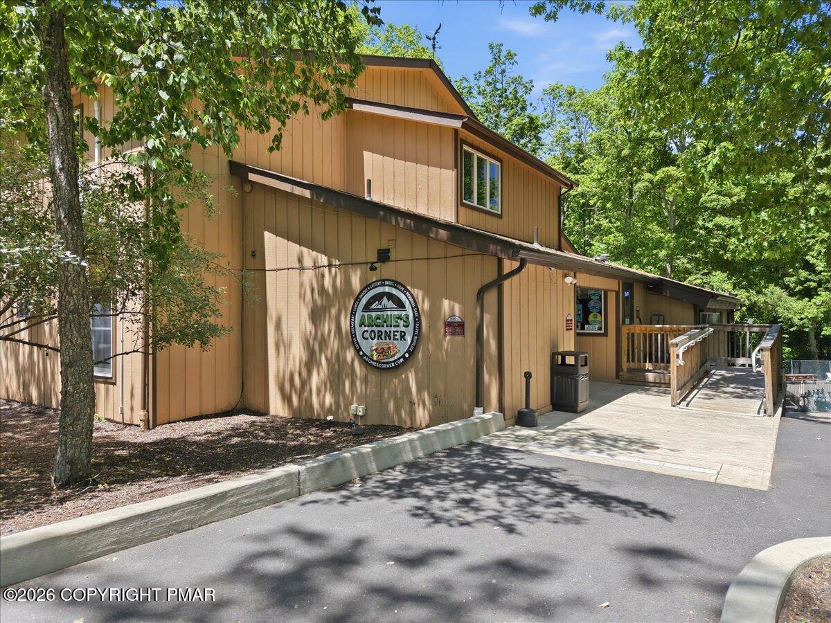 Tan, wood-sided building with an Archie's Corner sign and an accessibility ramp among leafy trees.