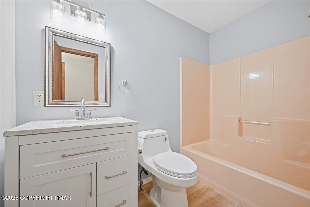 Bathroom with a white vanity, framed mirror, toilet, and peach-colored tub-shower surround.