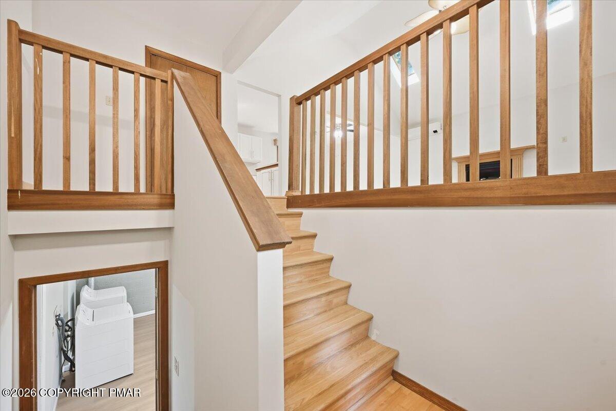 Wooden staircase and open-railed landing, with a laundry area visible below.