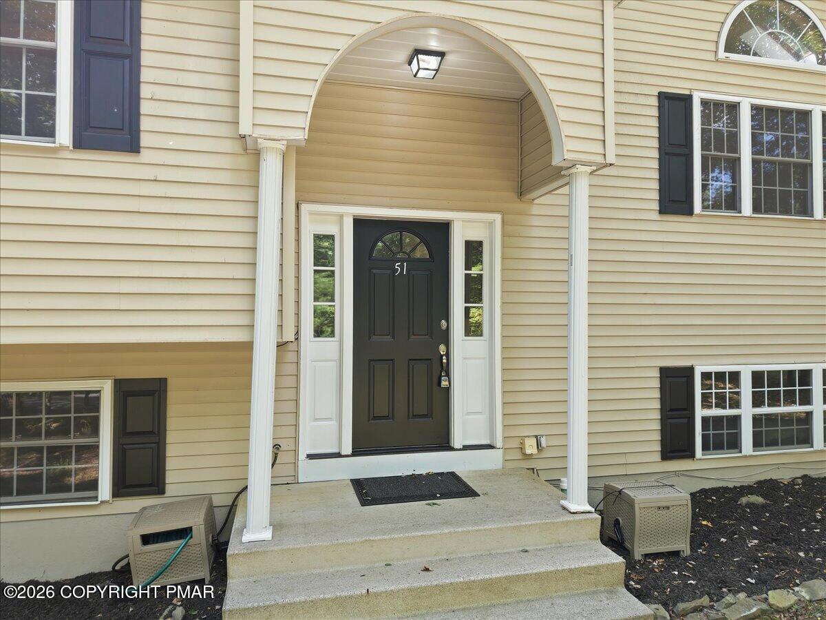 Home entrance with a black door marked 51 beneath an arched portico with white columns.
