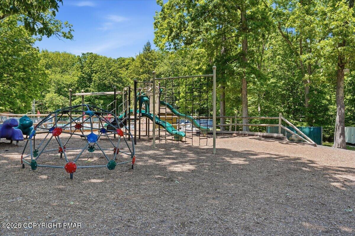 Wooded playground with climbing structures, slides, and a colorful climbing dome.