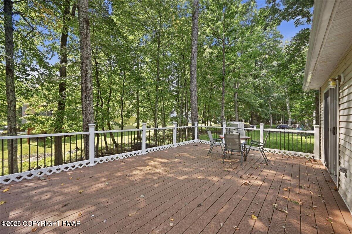 Wooden deck with patio seating overlooking a leafy wooded yard.