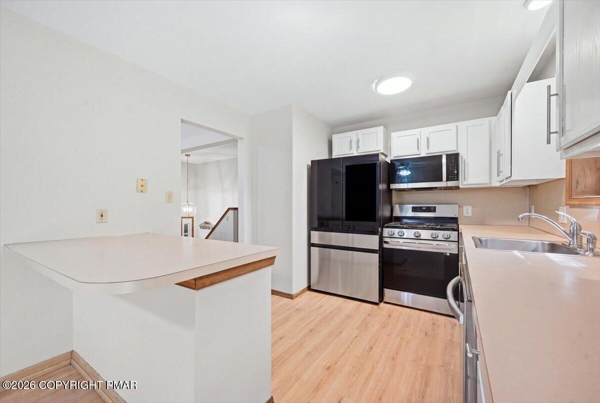 Kitchen with white cabinets, breakfast bar, and stainless steel appliances.